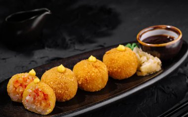 Soya sosu ve wasabi ile servis edilen nefis kızarmış suşi topları, parlak bir arka planda sunuluyor.