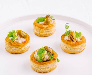 Exquisite puff pastry cases filled with savory filling, garnished with herbs on a sleek plate