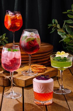 Sanatsal olarak sunulan çeşitli kokteyl koleksiyonu koyu, zarif bir zemin ve yeşillik