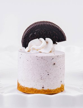 Süslü beyaz pasta standında çırpılmış krema ve kurabiye soslu üç mini kek.