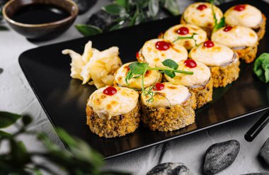 Modern bir masanın üstünde otlar ve sosla süslenmiş kaliteli suşi seçimi.