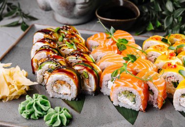 Delicious sushi rolls with fresh garnishes served on a modern plate, with soy sauce