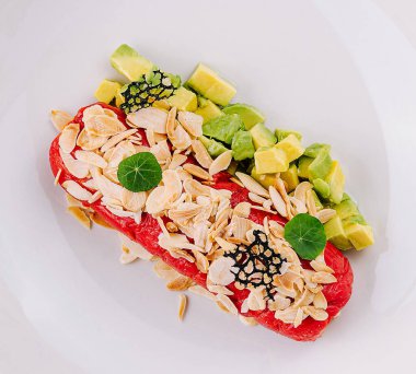 Top view of a delicious tuna poke bowl with avocado, sesame, and fresh vegetables, served on a white plate clipart