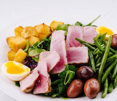 Vibrant and nutritious nicoise salad with seared tuna, greens, eggs, and potatoes