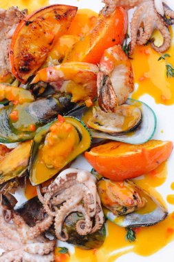 Keskin narenciye soslu ızgara deniz ürünleri içeren canlı bir tabak.