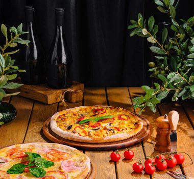 Rustic setting with variety of pizzas, fresh ingredients, and bottles of red wine