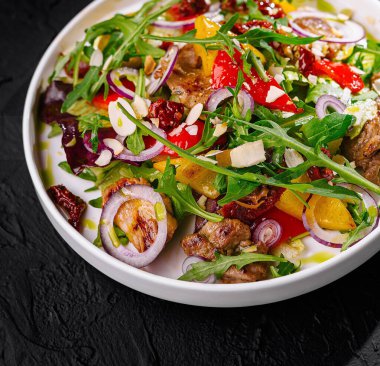 Vibrant mixed salad with greens, colorful vegetables, and seeds served on a dark background