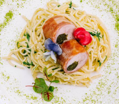 Top view of a delicious stuffed chicken breast on a bed of spaghetti garnished with herbs