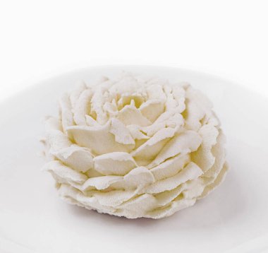 Beyaz arka planda izole edilmiş temiz bir tabakta zarif, yenilebilir çiçek pastası süslemesi.