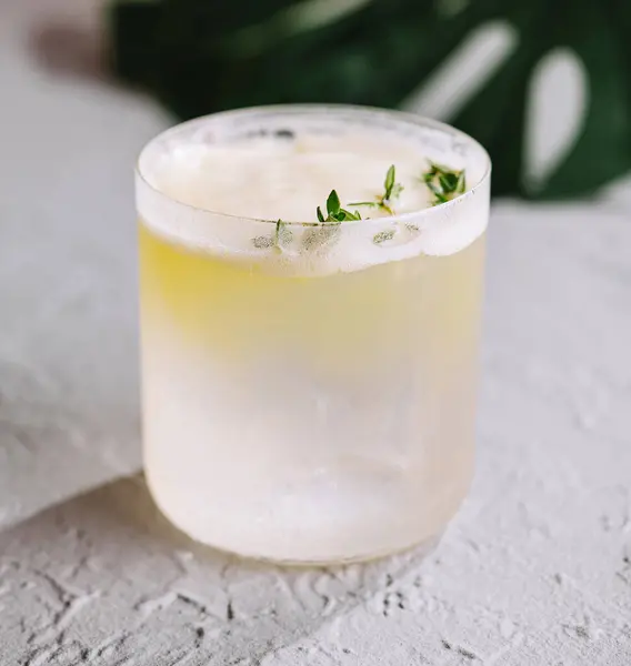 stock image Chilled cocktail with herbal garnish placed elegantly on a textured grey background