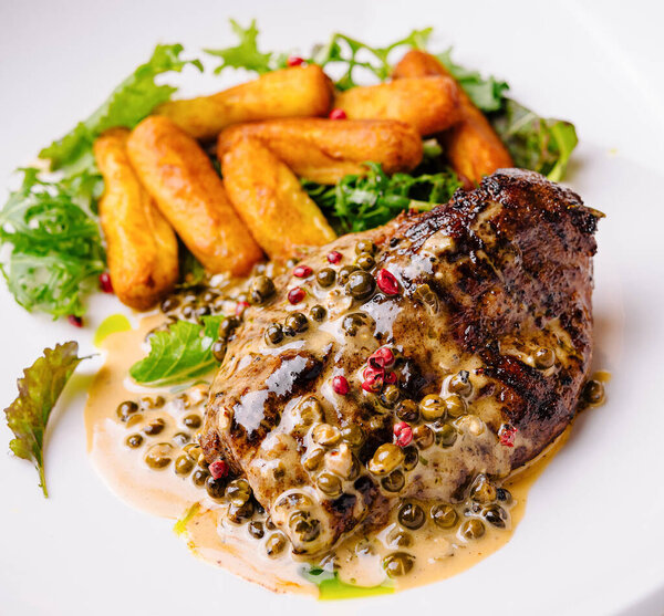 Delicious cooked steak drizzled with a creamy peppercorn sauce, served with golden potatoes and fresh salad