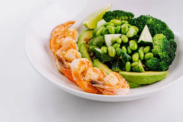 stock image Nutritious dish of grilled shrimp with broccoli, peas, and avocado on a pristine white plate