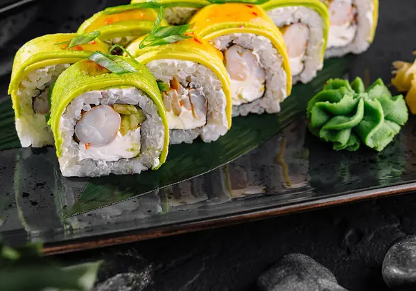 stock image Vibrant array of mango-topped sushi garnished with avocado and served with wasabi and ginger