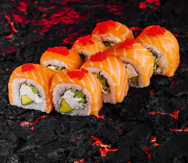 stock image Vibrant salmon sushi rolls on a unique black and red textured background