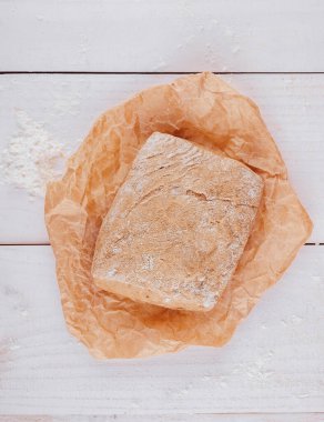 Üzerinde un serpiştirilmiş beyaz ahşap bir masanın üzerinde duran taze pişmiş ekmek somunu.