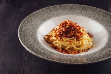 Peynir soslu spagetti ve güzel bir restoran ortamında servis edilen kızarmış pastırma parçaları.