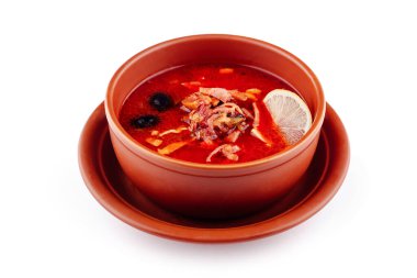 Beyaz arka planda kahverengi seramik kasede et, zeytin ve limonlu Solyanka çorbası.