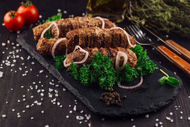Kırmızı soğanlı lezzetli kebaplar ve siyah bir tabakta tuz ve biberle tatlandırılmış otlar.