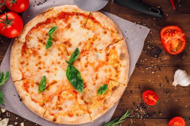 Kaba ahşap arka planda mozzarella peyniri ve fesleğen yapraklı taze pişmiş pizza margherita.