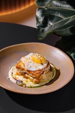 Baharatla süslenmiş, sosla süslenmiş ve restoranda servis edilen kızarmış yumurtalı Croque Madame.