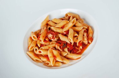Lezzetli bir İtalyan yemeği için beyaz tabakta servis edilen domates soslu makarna.