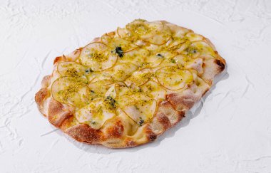 Beyaz arka planda armut dilimli, mavi peynirli, fıstıklı ve mozzarella peynirli taze pişmiş pizza.