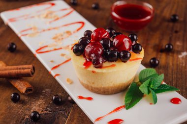 Böğürtlen soslu ve ahşap masada servis edilen lezzetli mini cheesecake.