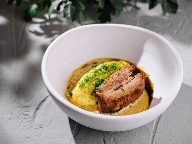 Kremalı yaban havucu püresi ve aromalı kahverengi sosla birlikte servis edilen hafif pişmiş sığır eti kısa kaburgası içeren mutfak başyapıtı.
