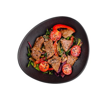 Susam tohumlu biftek ve sebzeli sıcak salata, siyah tabakta servis edilir, beyaz arka planda çekilir.