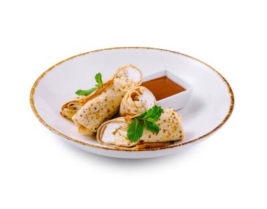 Süzme peynirli ince krepler ve nane yapraklarıyla süslenmiş muz dilimleri beyaz tabakta tatlı soslu.