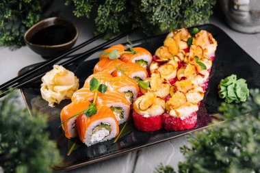 Somon ile taze suşi ruloları ve mikroyeşilliklerle süslenmiş soya sosu, wasabi ve zencefil ile servis edilir.