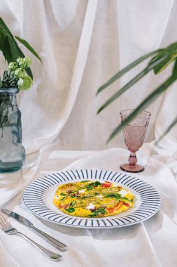 Kahvaltı için domatesli lezzetli omlet ve ıspanak şık tabakta servis edilir.