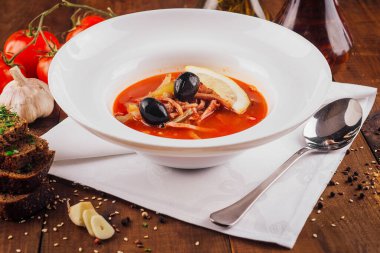 Bir kase geleneksel Rus çorbası solyanka ahşap bir masada servis edilir.