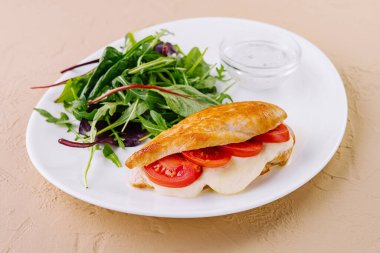 Mozarella ve domatesle doldurulmuş ızgara tavuk göğsü. Taze salata ve beyaz sosla servis ediliyor.