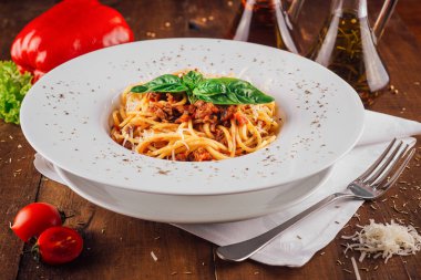 Parmesan peynirli spagetti bolonez ve ahşap masada fesleğen.