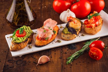 Tabak çeşitli lezzetli İtalyan aperatifleri sunuyor kızarmış baget dilimleri üzerinde bruschetta.