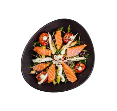 Somon, avokado ve kiraz domatesli taze ve sağlıklı salata, susam tohumu ve sos ile tatlandırılmış, siyah bir tabakta servis edilir.