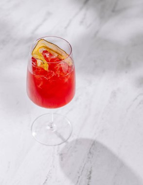Kırmızı kokteyl beyaz mermer masada duruyor ve gölgesi var.