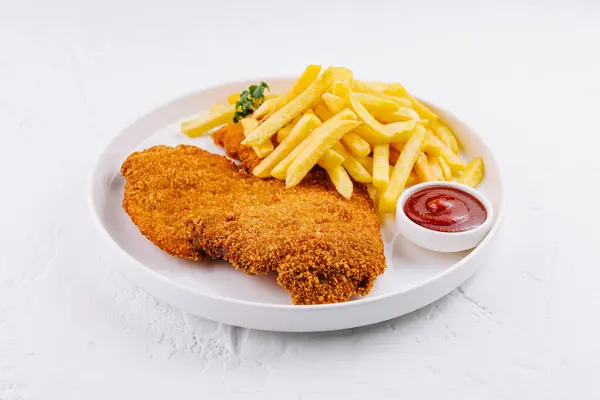 Patates kızartması ve ketçapla servis edilen iki parça kızarmış tavuk göğsü.