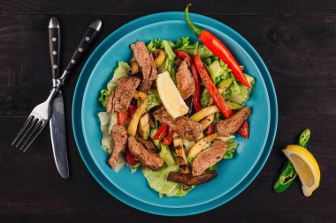 Izgara dana etli sıcak salata, koyu ahşap arka planda patates ve biber, sağlıklı yemek, üst manzara.