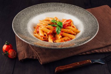 Lezzetli makarna tabağı domates sosu ve fesleğen garnitürle sunulur.