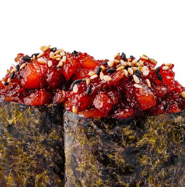 Baharatlı ton balıklı iki Gunkan suşisi beyaz bir yüzeye susam tohumları serpiştirilmiş.