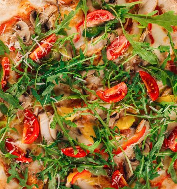 Lezzetli taze pişmiş roka ve kiraz domatesli pizza masanın üzerinde duruyor, yukarıdan çekilmiş.