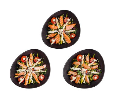 Somon, karides, avokado ve marullu siyah oval tabakta üç salata. Beyaz arka planda güzelce düzenlenmiş ve çekilmiş.
