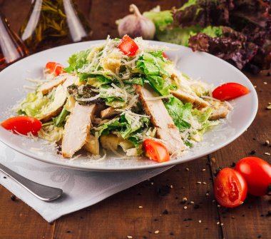 Geleneksel sezar salatası ızgara tavuk fileto, marul, parmesan peyniri, vişneli domates ve karabiberli kızarmış ekmek.