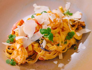 Taze otlarla süslenmiş karides, mantar ve tıraş edilmiş parmesan peynirli tagliatelle makarnası.