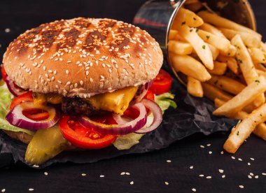 Taze çizburger, patates kızartması ve ketçap ile ahşap bir masanın üzerinde.