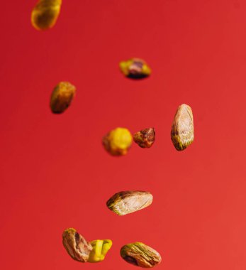 Kırmızı zemin üzerine düşen açık kabuklu fıstıklar.