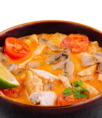 Baharatlı Thai Tom çorbası, içinde tavuk, mantar, domates ve limon bulunan kahverengi bir kasede servis ediliyor.