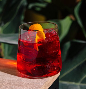 Buzlu taze bir kokteyl ve portakal kabuğu masanın üzerinde duruyor.